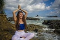 Outdoors portrait of young beautiful and happy red hair woman practicing yoga and meditation exercise in lotus position at beach Royalty Free Stock Photo