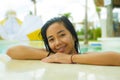 Outdoors portrait of young beautiful and sweet Asian Indonesian teenager girl swimming at tropical resort pool smiling happy and Royalty Free Stock Photo