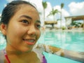 Outdoors portrait of young beautiful and sweet Asian Indonesian teenager girl swimming at tropical resort pool smiling happy and Royalty Free Stock Photo