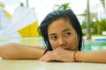 Outdoors portrait of young beautiful and sweet Asian Indonesian teenager girl swimming at tropical resort pool smiling happy and Royalty Free Stock Photo