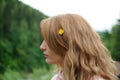 Outdoors portrait of young calm blonde woman in pink clothes with little yellow flower in her long hair on the hill with Royalty Free Stock Photo