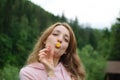 Outdoors portrait of young calm blonde woman in pink clothes with little yellow flower in her mouth on the hill with Royalty Free Stock Photo