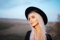 Outdoors portrait of young cute blonde girl wearing black hat. Royalty Free Stock Photo