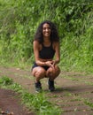 Outdoors portrait of young happy and attractive hispanic woman with curly hair and athletic body squatting cheerful and carefree Royalty Free Stock Photo