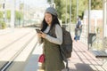 Outdoors portrait of young happy and beautiful Asian Chinese tourist woman with backpack using mobile phone on train station Royalty Free Stock Photo