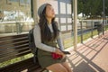 Outdoors portrait of young happy and beautiful Asian Japanese tourist woman with backpack sitting cheerful on train station bench Royalty Free Stock Photo