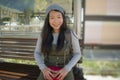 Outdoors portrait of young happy and beautiful Asian Korean tourist woman with backpack sitting cheerful on train station bench Royalty Free Stock Photo