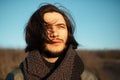 Outdoors portrait of young thoughtful man with long hair in windy day on blue sky background. Royalty Free Stock Photo