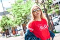 Outdoors Recreation. Teen girl student in denim jacket and sunglasses walking on urban background posing to camera cool Royalty Free Stock Photo