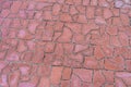 Outdoors red pavement covering large area. Footpath paved with tiled stone