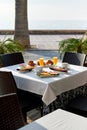 Outdoors restaurant. Table setting with classic breakfast. Orange juice, fruits and pastries