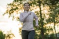 Outdoors running workout - young happy and dedicated Asian Japanese woman jogging at beautiful city park or countryside trail on Royalty Free Stock Photo