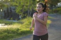 Outdoors running workout - young happy and dedicated Asian Japanese woman jogging at beautiful city park or countryside trail on Royalty Free Stock Photo