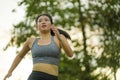 Outdoors running workout - young happy and dedicated Asian Korean woman jogging at beautiful city park or countryside trail on Royalty Free Stock Photo