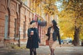 Outdoors shot of young women with coffee on city street. Two fashion girls walking outdoor with cofee. Streetfashion friends Royalty Free Stock Photo