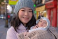 Outdoors urban lifestyle portrait of young happy and beautiful Asian Chinese woman as mother of little adorable baby girl holding Royalty Free Stock Photo