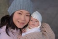 Outdoors urban lifestyle portrait of young happy and beautiful Asian Korean woman as mother of little adorable baby girl holding Royalty Free Stock Photo