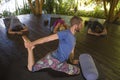 Outdoors yoga lesson - group of young people and coach man practicing relaxation exercise at Asian wellness retreat hut training Royalty Free Stock Photo