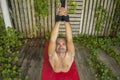 Outdoors yoga workout - attractive and happy man doing aero yoga on red mat hanging from ropes training body balance and Royalty Free Stock Photo