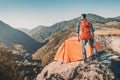 Outdoorsman traveler with backpack stands on cliff with his tent with a gorgeous view of a mountain valley in Armenia. Camping