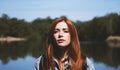 Outdoorsy young woman standing by lake in harsh light Royalty Free Stock Photo