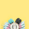 Outfit for beach and tropical vacations, straw beach sun hat, towel, sunglasses on yellow. Summer concept Royalty Free Stock Photo