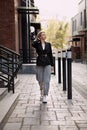 Outfit fashion, young stylish businesswoman wearing oversized black jacket, grey jeans and trendy white sneakers.