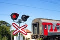 The outgoing train travels through the level crossing with the traffic light on. Convenient fast transportation