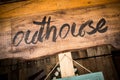 Outhouse sign on wooden board Royalty Free Stock Photo