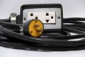 Outlet and out focus yellow plug with black cable on the white background. Royalty Free Stock Photo