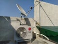 Outlet of an split air conditioner kept on the roof top. A direct to satellite television antenna.