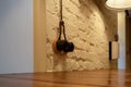 Vintage electric black socket with twisted wire on a white brick wall over an empty wooden table in a cafe.