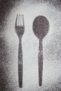 Outline of a fork and spoon in white powdered sugar.