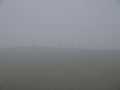 The outline of an unidentifiable single walker on a hill in thick mist and cloud