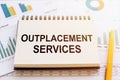 OUTPLACEMENT SERVICES open book on table and finncial graphs. Business concept