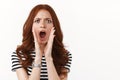 Outraged angry young redhead woman in striped t-shirt accuse someone, cup hands around opened mouth, cursing bad person