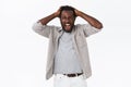 Outraged and distressed african-american bearded man yelling from grief and loss, holding hands on head, shouting with Royalty Free Stock Photo