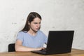 Outraged girl typing on a laptop, sitting at the table