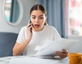 Outraged woman with documents in her hands talking on mobile phone