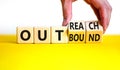 Outreach or outbound symbol. Businessman turns wooden cubes and changes the word `outbound` to `outreach`. Beautiful yellow ta