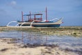 Outrigger boat on the beach during low tide Royalty Free Stock Photo