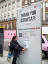 Outside Bond St station, a public stay safe sign board and free hand sanitiser.