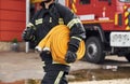 Outside near truck and with fire hose in hands. Woman in uniform is at work in department