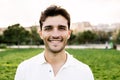 Outside portrait of young smiling handsome man looking at camera at city park. Royalty Free Stock Photo