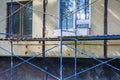 Outside repair and renovation of apartment house, blue metal scaffolding tower