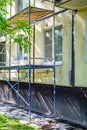 Outside repair and renovation of apartment house, blue metal scaffolding tower