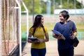 Outside of school, a happy young couple of students stands along a fence, studying a book Royalty Free Stock Photo