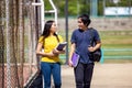 Outside of school, a happy young couple of students stands along a fence, studying a book Royalty Free Stock Photo