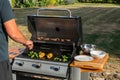 Man grilling food on barbecue outside in the sunshine. Meat and vegetables being cooked on a BBQ. Royalty Free Stock Photo