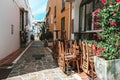 Outside view of a closed cafe during early morning in Spain. Bright sun making shadows on stacked chairs and colorful yellow and